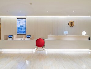 A modern reception area with a digital display, a wooden sign with Chinese characters, and a red chair.