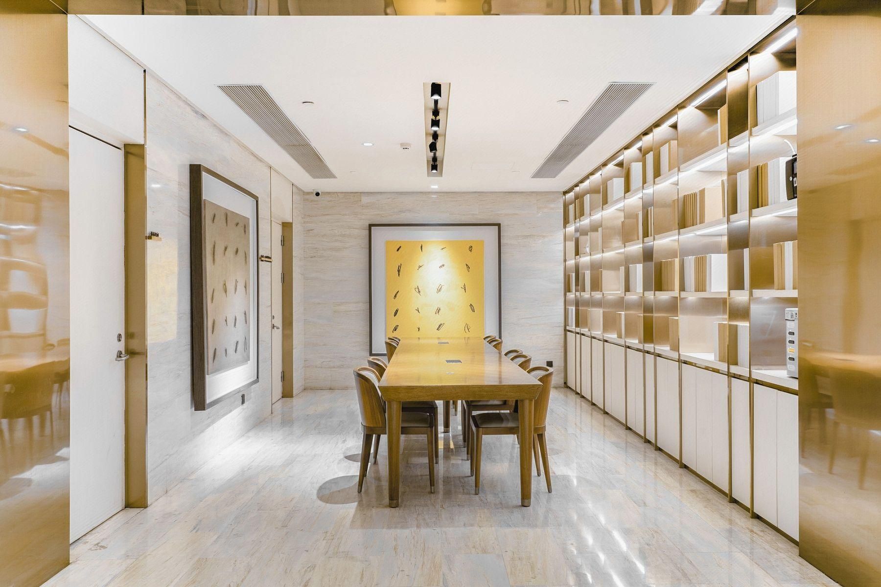 A modern conference room with a long table, chairs, and a bookshelf.