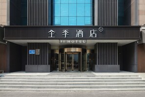 A hotel entrance with a modern facade, a revolving door, and a sign indicating the name 'JI HOTEL'. - Ji Hotel (Jinan)