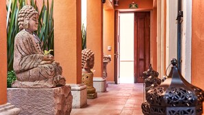 A corridor with stone statues and a decorative metal lantern. - Luxury Villa B&B (San Miguel de Allende)