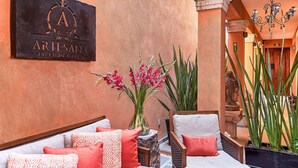 A cozy outdoor seating area with a sofa and chairs, a decorative wall sign, and potted plants. - Luxury Villa B&B (San Miguel de Allende)