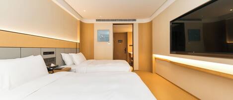 Habitación de hotel con dos camas, un televisor grande y una mesita de noche.