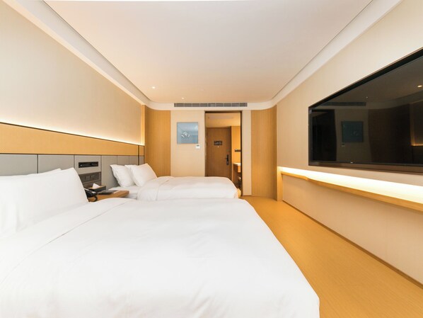 Quarto de hotel com duas camas, uma televisão grande e uma mesinha de cabeceira.