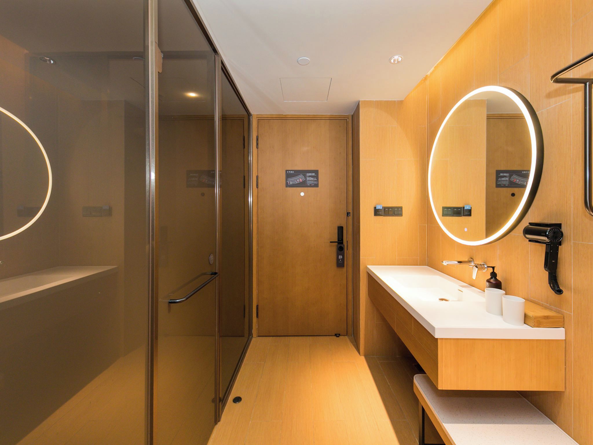 A modern bathroom with a glass shower enclosure, a wooden vanity with a sink, and a large mirror.