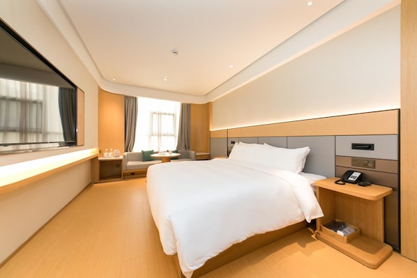 Une chambre d’hôtel moderne avec un grand lit, une table de chevet avec un téléphone et une fenêtre avec des rideaux.