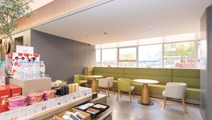 Een modern caféinterieur met zitplaatsen, een drankencarrousel en uitzicht op de straat.