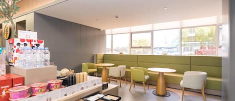 Un interior de cafetería moderna con asientos, una exhibición de bebidas y vistas a la calle.