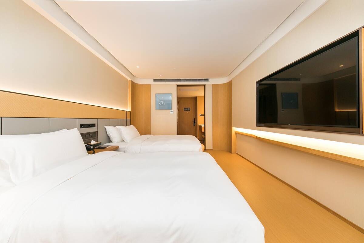 A hotel room with two beds, a large window, and a bedside table.