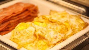 A breakfast plate with scrambled eggs and bacon.