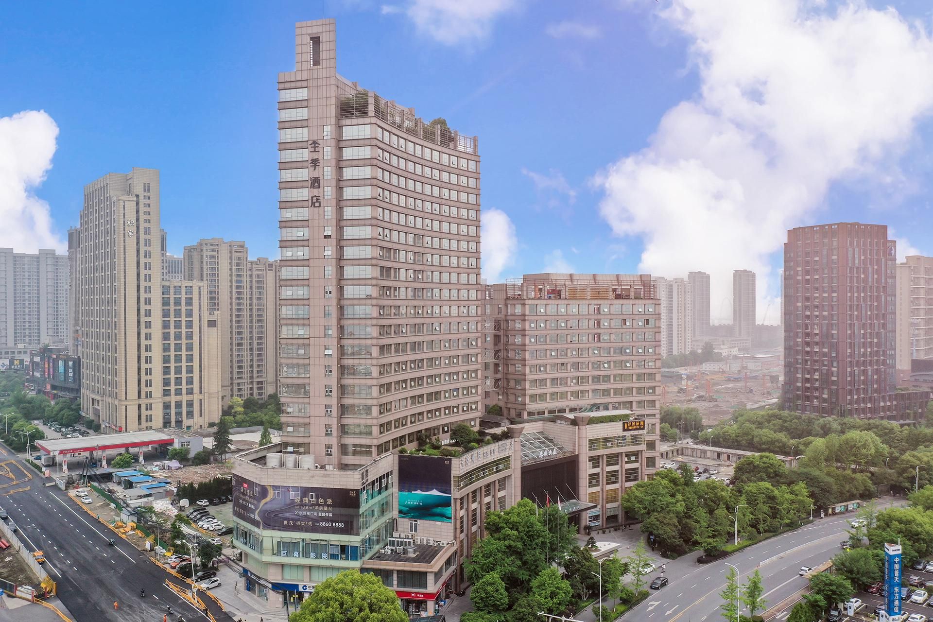 A high-rise hotel with multiple floors, surrounded by other buildings and a clear sky.