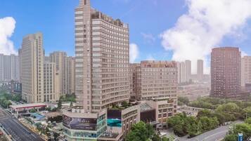 A high-rise hotel with multiple floors, surrounded by other buildings and a clear sky.
