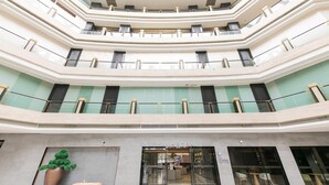 Een hotel lobby met meerdere niveaus, een centraal atrium, glazen balustrades en een receptiebalie.