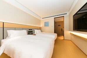 Habitación de hotel con una cama grande, controles junto a la cama, una mesita pequeña y una ventana.