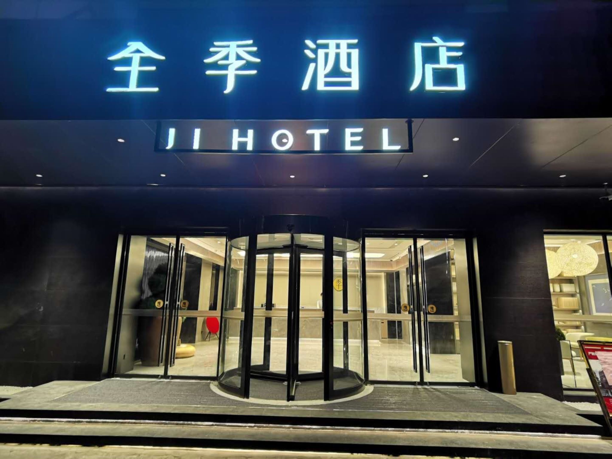 The entrance to Ji Hotel with a revolving door and glass doors.