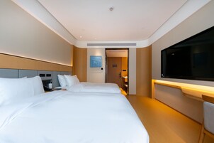 Una habitación de hotel con dos camas, un televisor y un escritorio con una silla.