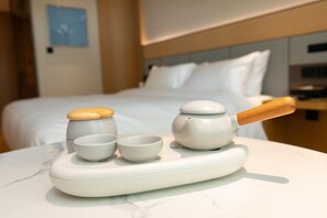 A neatly arranged tea set on a marble table in a hotel room with a bed in the background. - Ji Hotel (Hefei)
