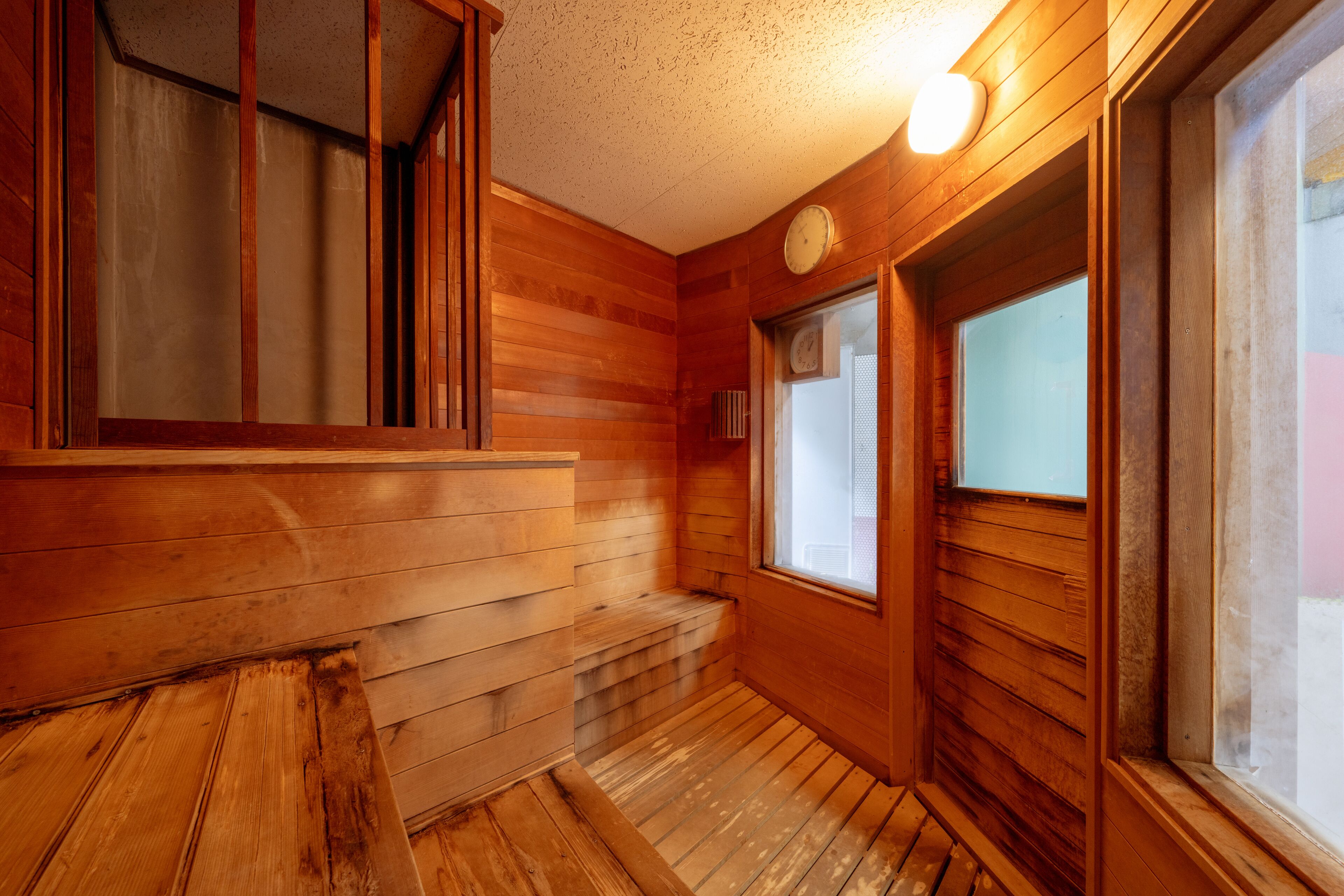 Un intérieur en bois avec un banc, une fenêtre et une horloge.