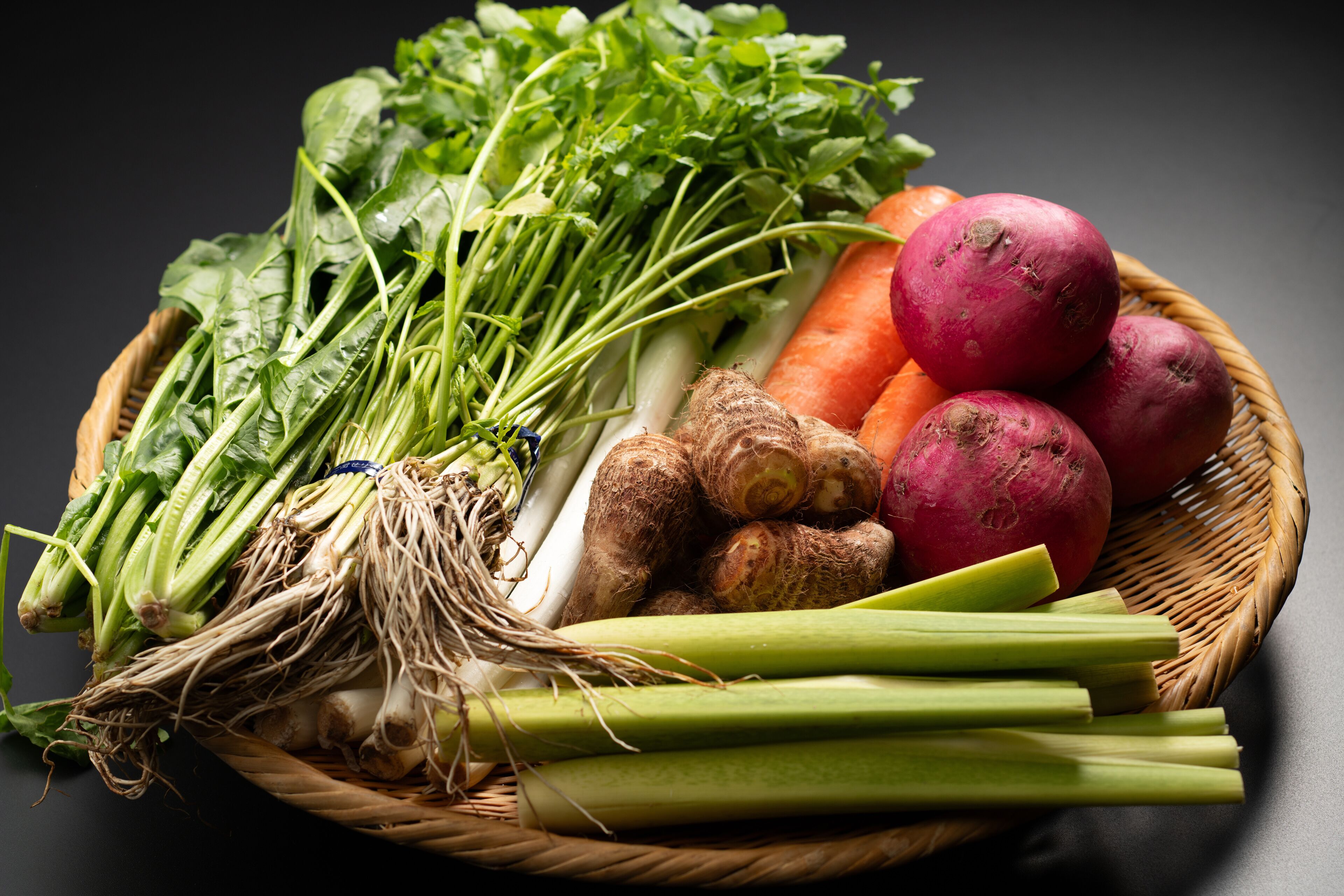 A basket of fresh vegetables including carrots, potatoes, and leafy greens.