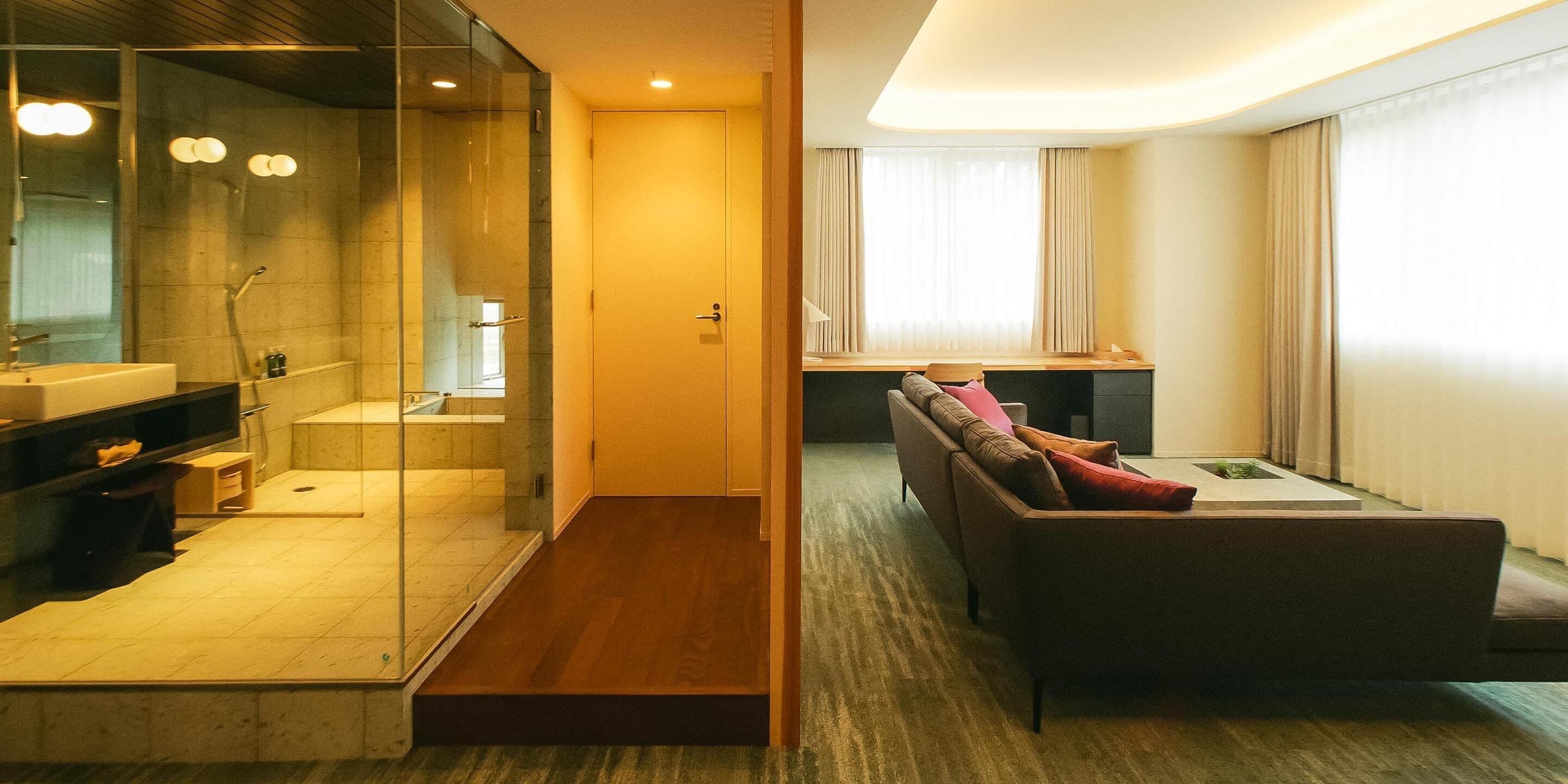 Una habitación de hotel moderna con cabina de ducha de vidrio, un sofá y una pequeña mesa.