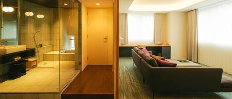 Una habitación de hotel moderna con cabina de ducha de vidrio, un sofá y una pequeña mesa.