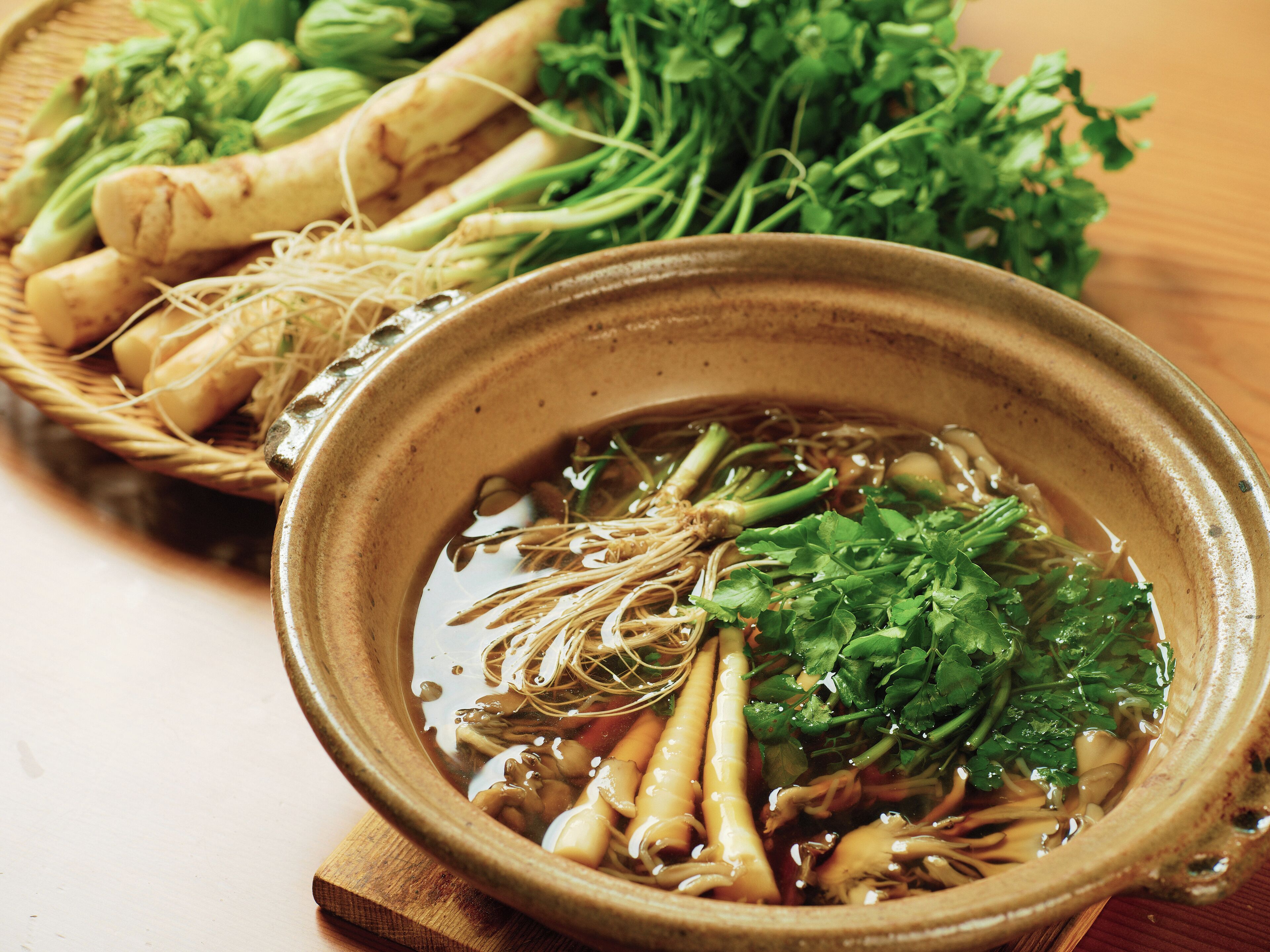 A bowl of soup with various vegetables and herbs.