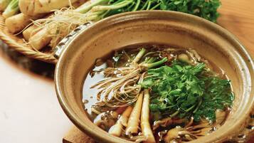 A bowl of soup with various vegetables and herbs.