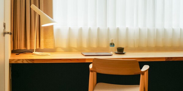 A wooden desk with a laptop, a lamp, a cup, and a bottle of water. - hotel yutoria fujisato (Fujisato)
