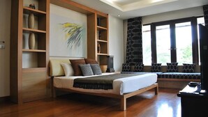 A bedroom with a large bed, wooden shelving, a painting, and a view through large windows. - DDM Siam Thailand (Bang Lamung)