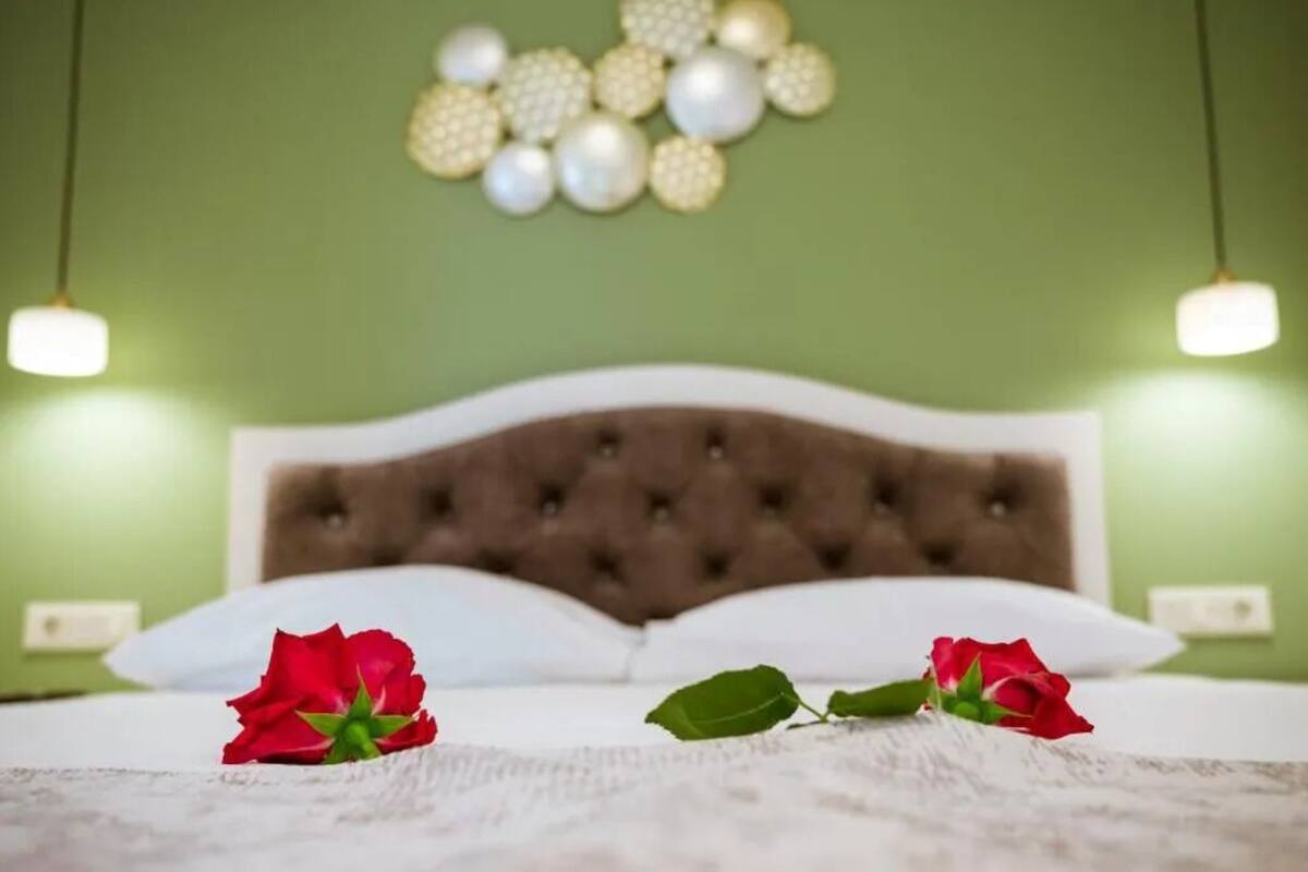 Un lit avec des oreillers blancs et une tête de lit capitonnée, un mur vert et des ornements sphériques décoratifs.