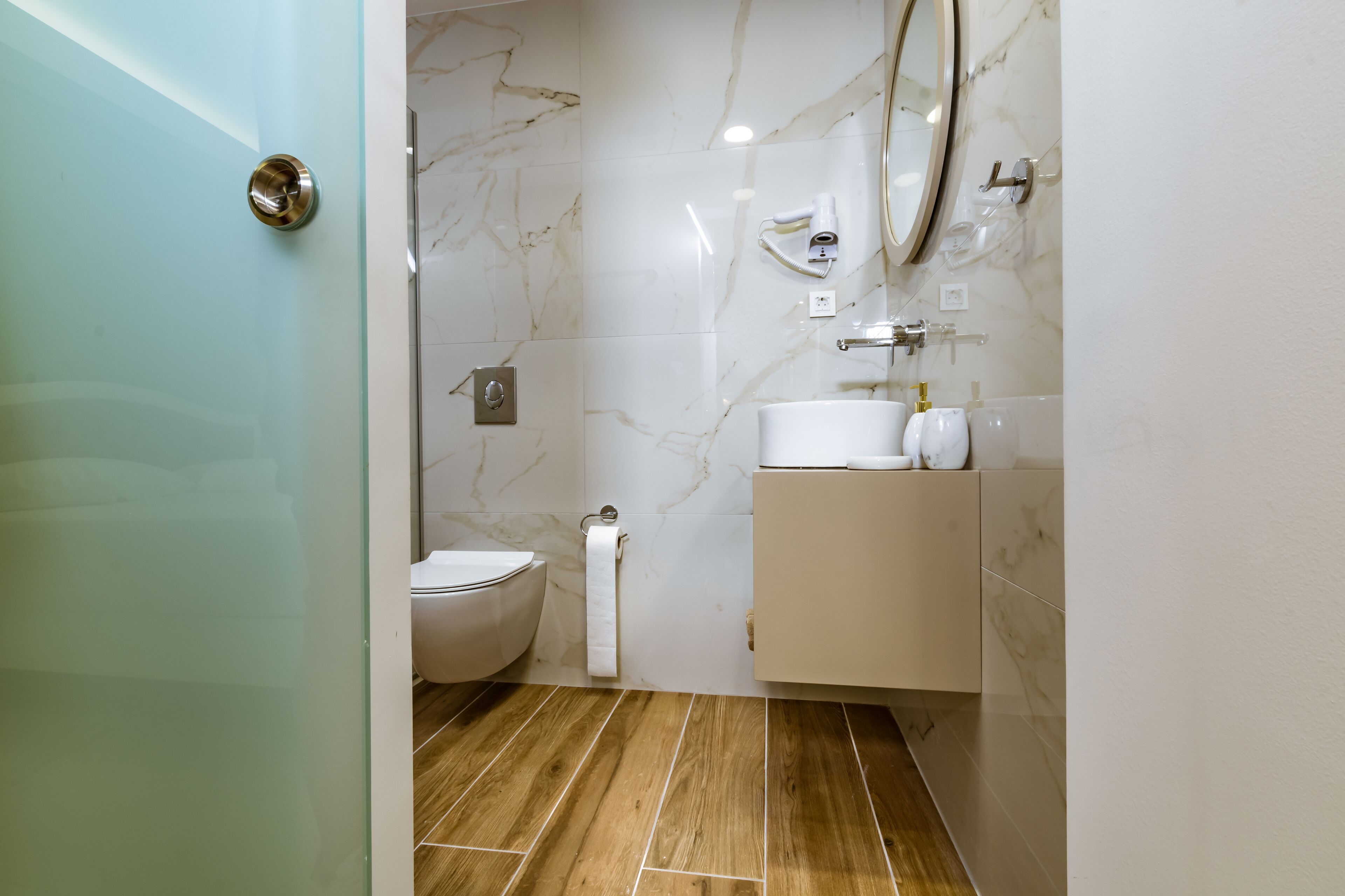 A modern bathroom with a toilet, a sink, a mirror, and a shower area.