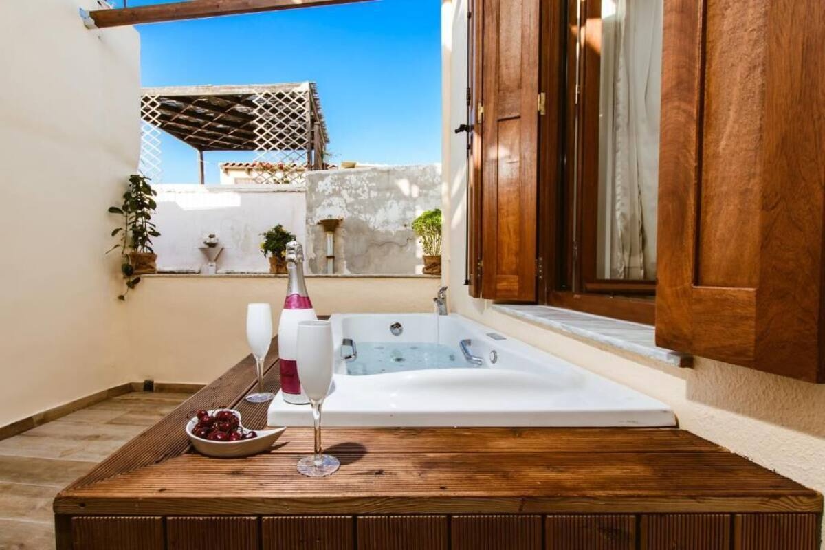Une table en bois, un verre de vin, un saladier de fruits et un jacuzzi.