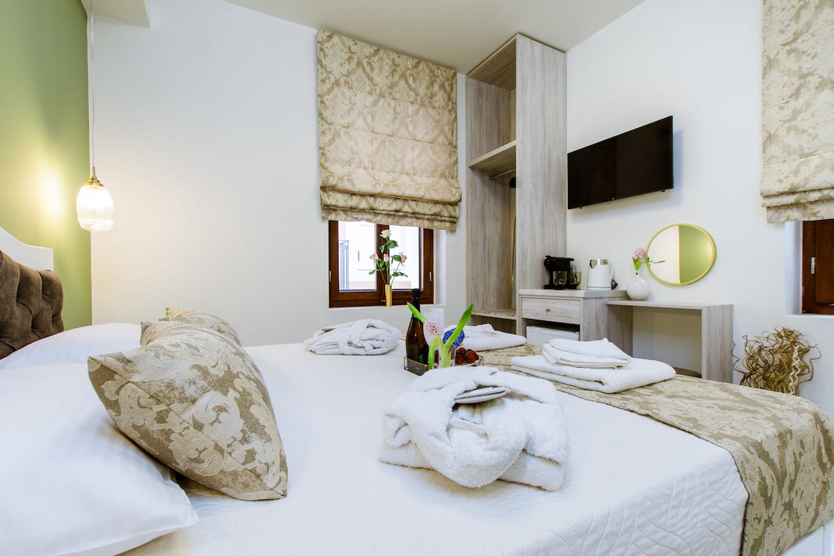 Une chambre d’hôtel avec un lit, une table de chevet, un miroir, une télévision et une fenêtre donnant sur un paysage agréable.
