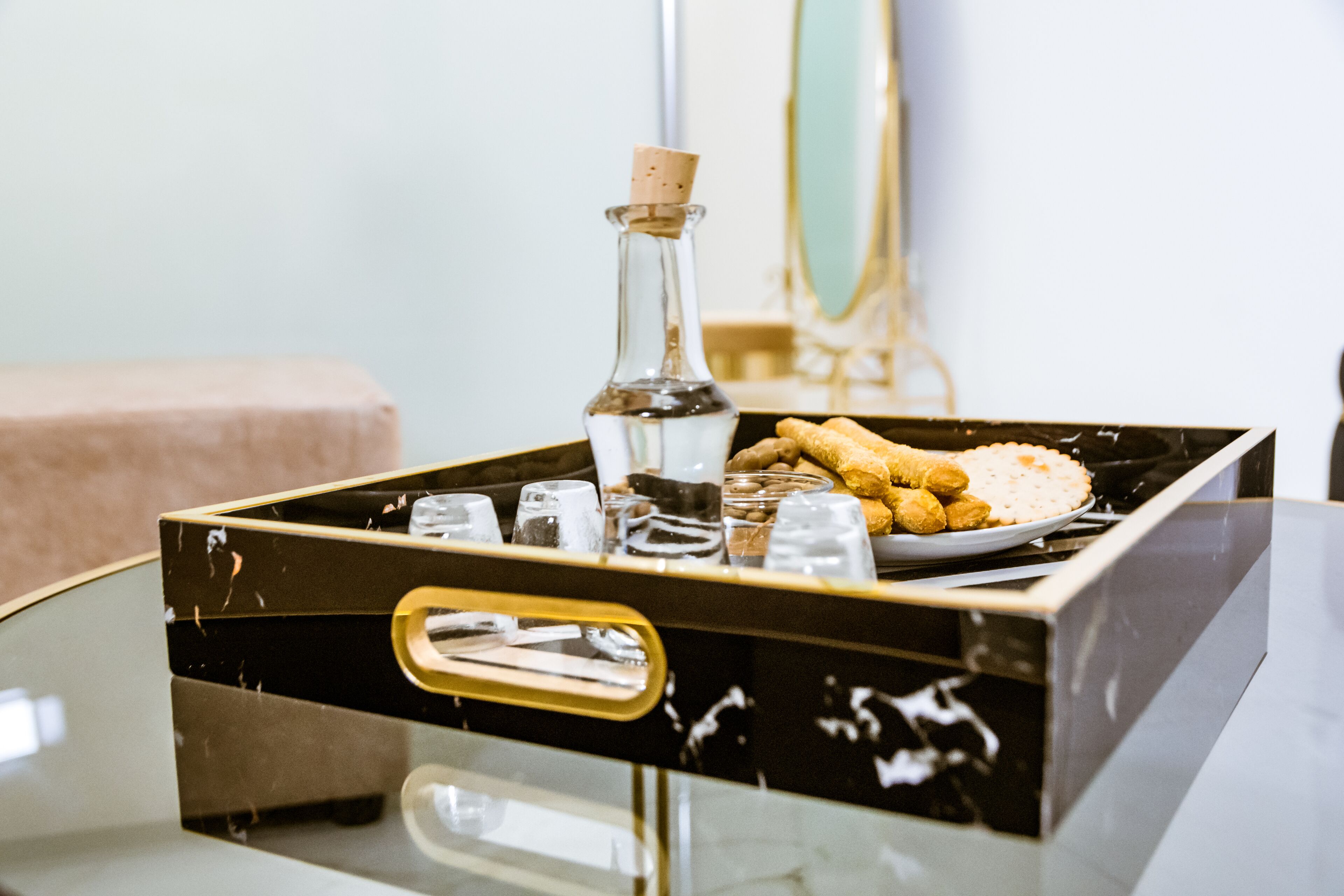 Eine schwarze Minibar mit einer Flasche, Gläsern und einer Speisenplatte.