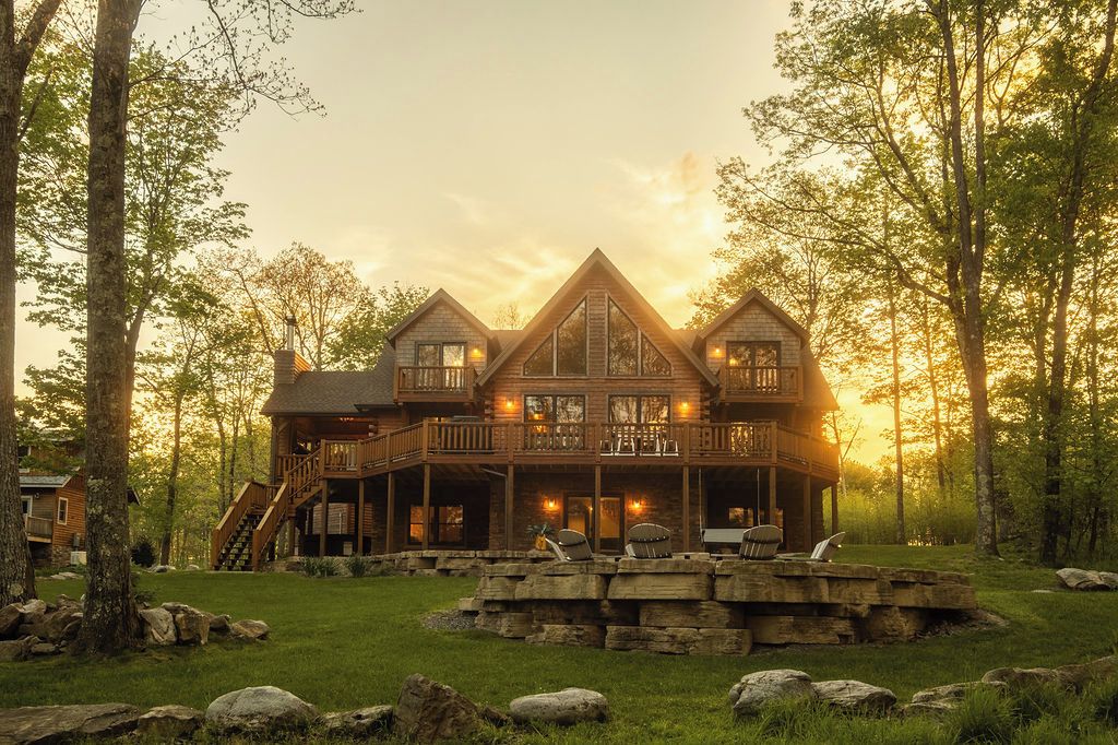Una cabaña grande de madera con un balcón, una escalera y una chimenea de piedra.