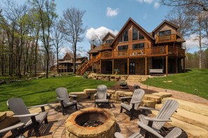 A large log cabin with a stone patio, Adirondack chairs, and a fire pit. - A Lil Slice of Heaven by Taylor Made Deep Creek (McHenry)