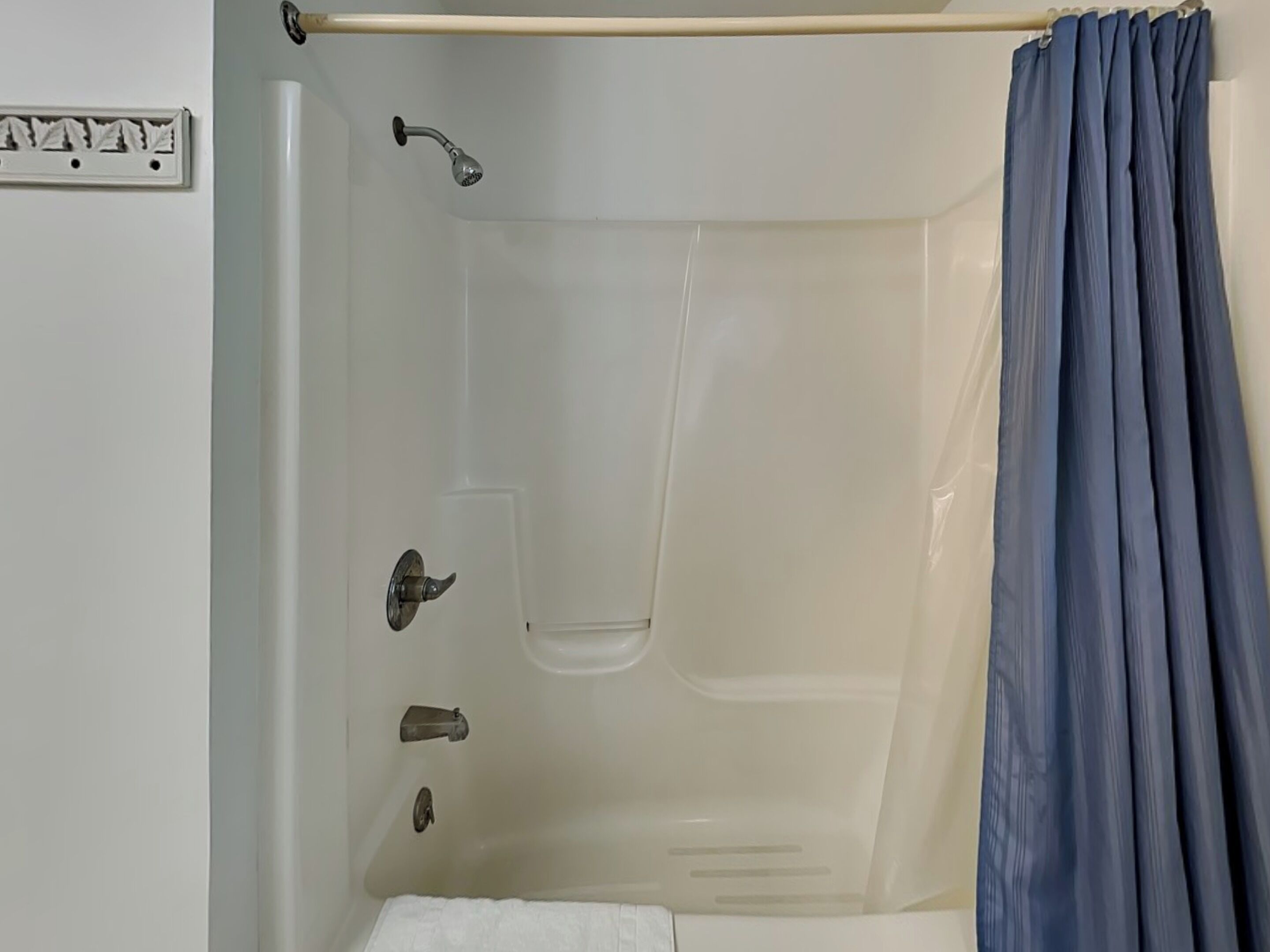 A bathtub with a showerhead, a towel rack, and a curtain.