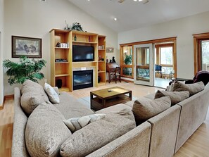 A living room with a sofa, coffee table, fireplace, TV, and bookshelves. - A Wonderful Place by Taylor Made Deep Creek (Swanton)