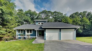 Une maison à deux étages avec un garage, un porche à l’avant et une allée menant au garage.