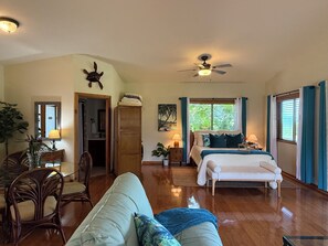 Um quarto amplo com cama, sofá, área de refeições e ventilador de teto.