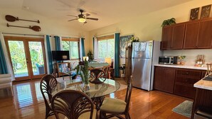 Una cocina moderna con comedor, armarios de madera, refrigerador y ventilador de techo.