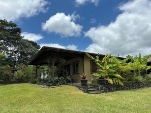 Une maison dotée d’un porche abrité, entourée d’une végétation luxuriante et d’une pelouse bien entretenue.