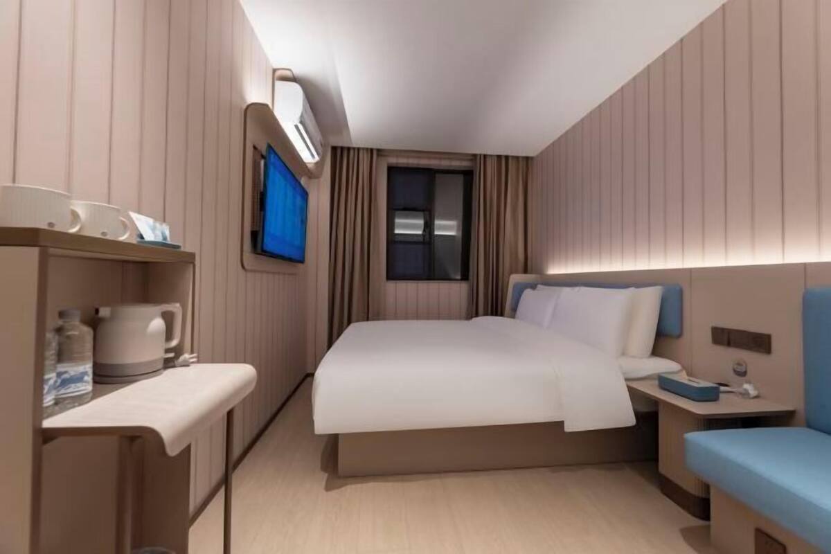 Une chambre d’hôtel moderne équipée d’un lit, d’une table de chevet et d’un petit coin salon.