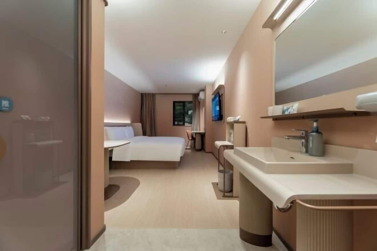 Une chambre d’hôtel avec un lit, une table de chevet et un grand miroir.