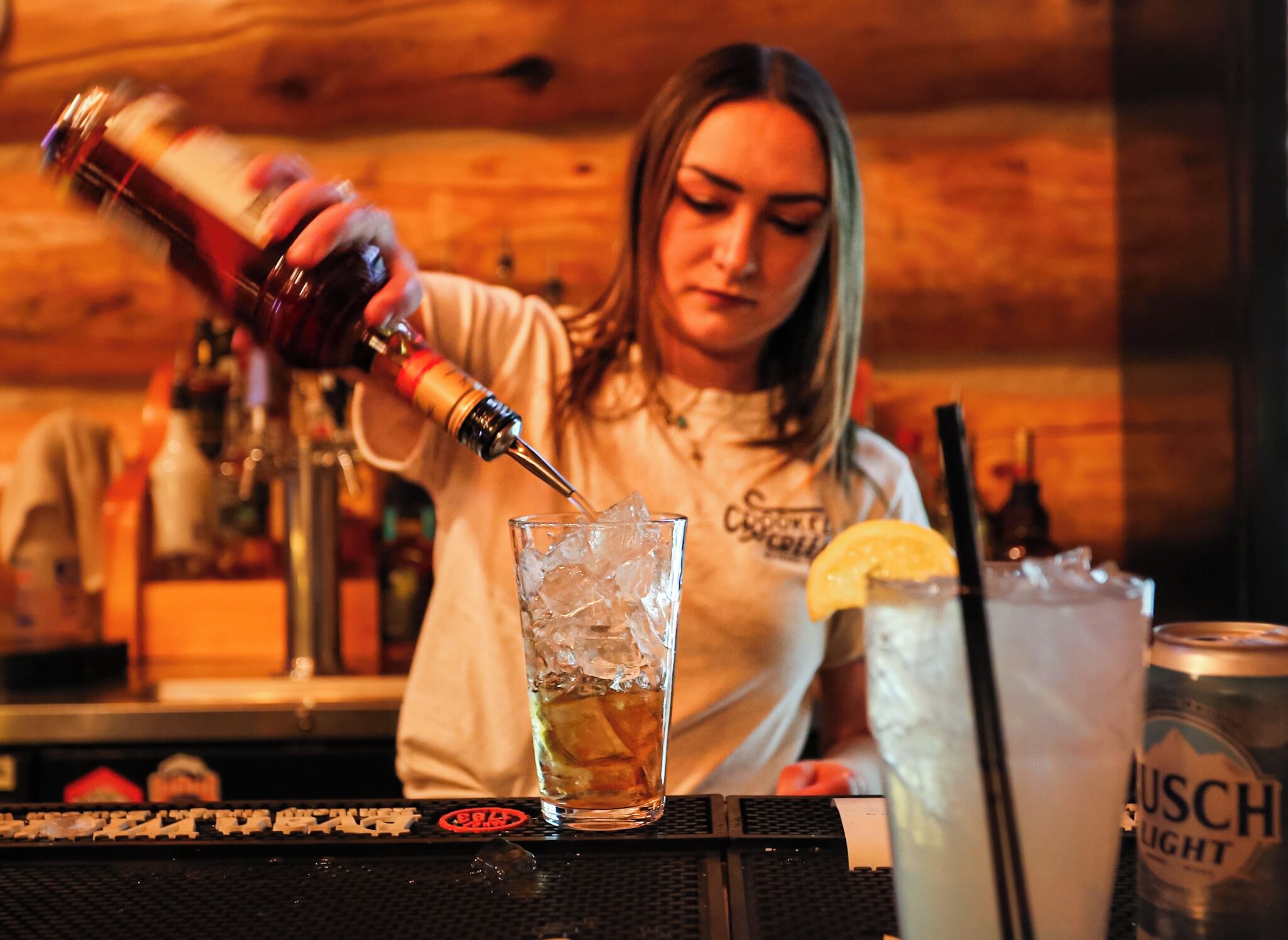 Een barman schenkt een drankje in met ijs.