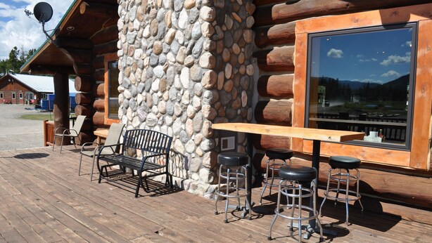 A wooden deck with a stone pillar, a wooden table, and bar stools. - Crooked Creek (Dubois)