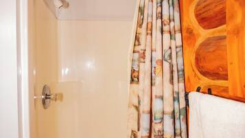 Une douche avec un rideau de douche à motifs de bambou, un panneau mural en bois et une tringle de douche en métal.