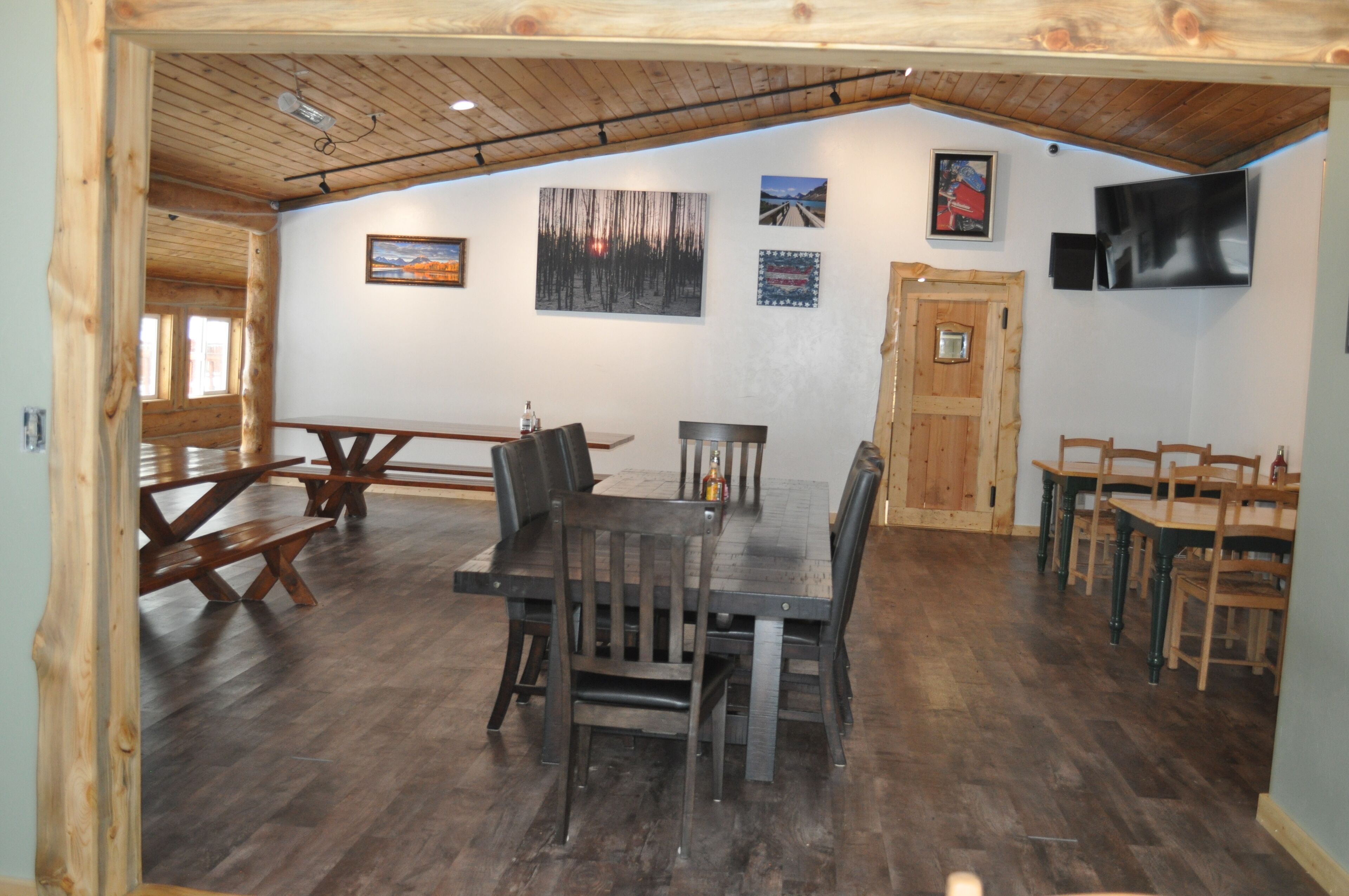 A dining area with wooden tables and benches, a wooden ceiling, and wall-mounted artwork.
