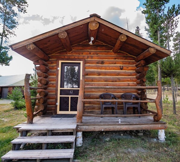 A log cabin with a porch, two chairs, and a door marked with the number 12.