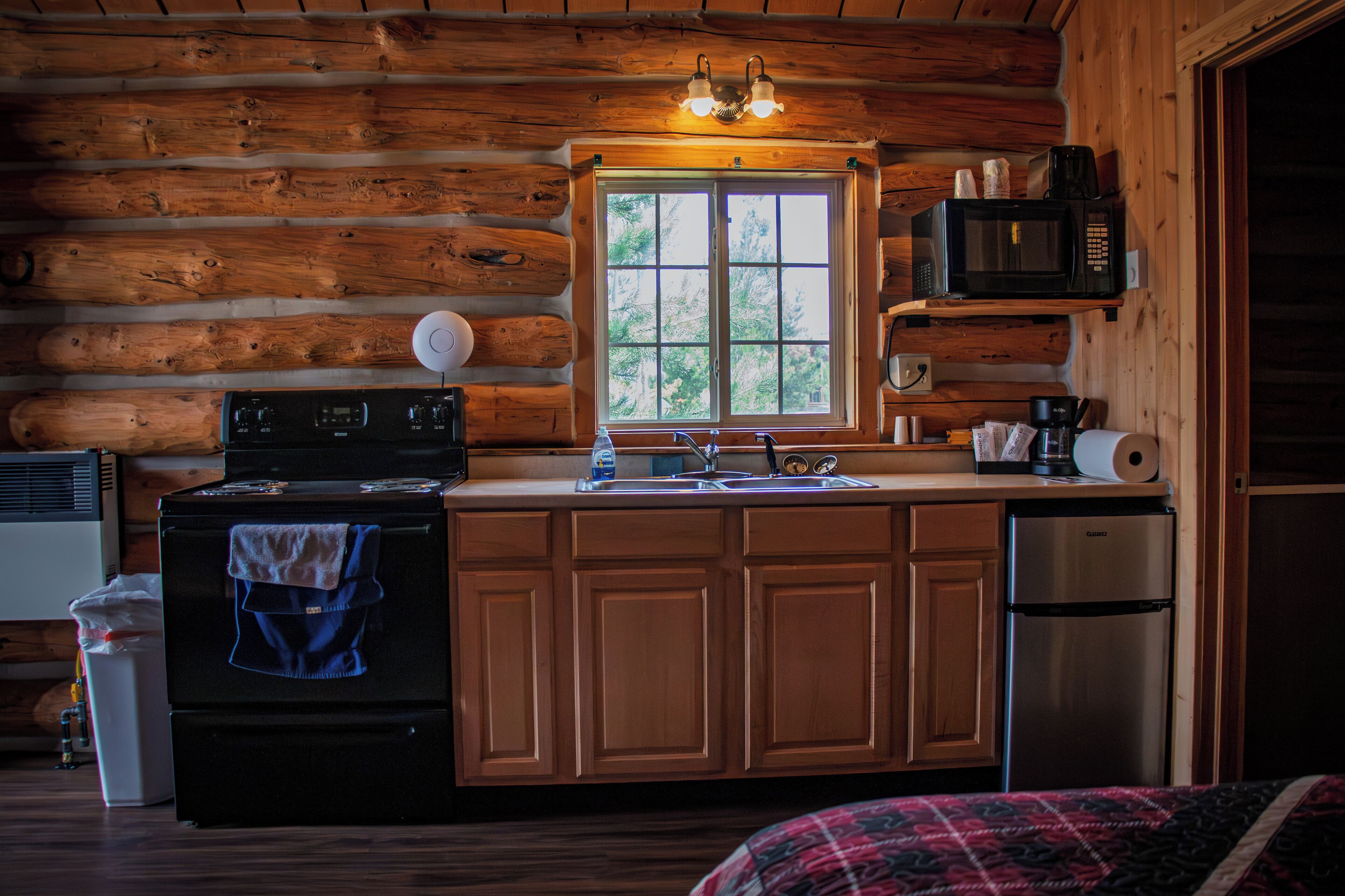 A log cabin kitchen with a stove, sink, and refrigerator.