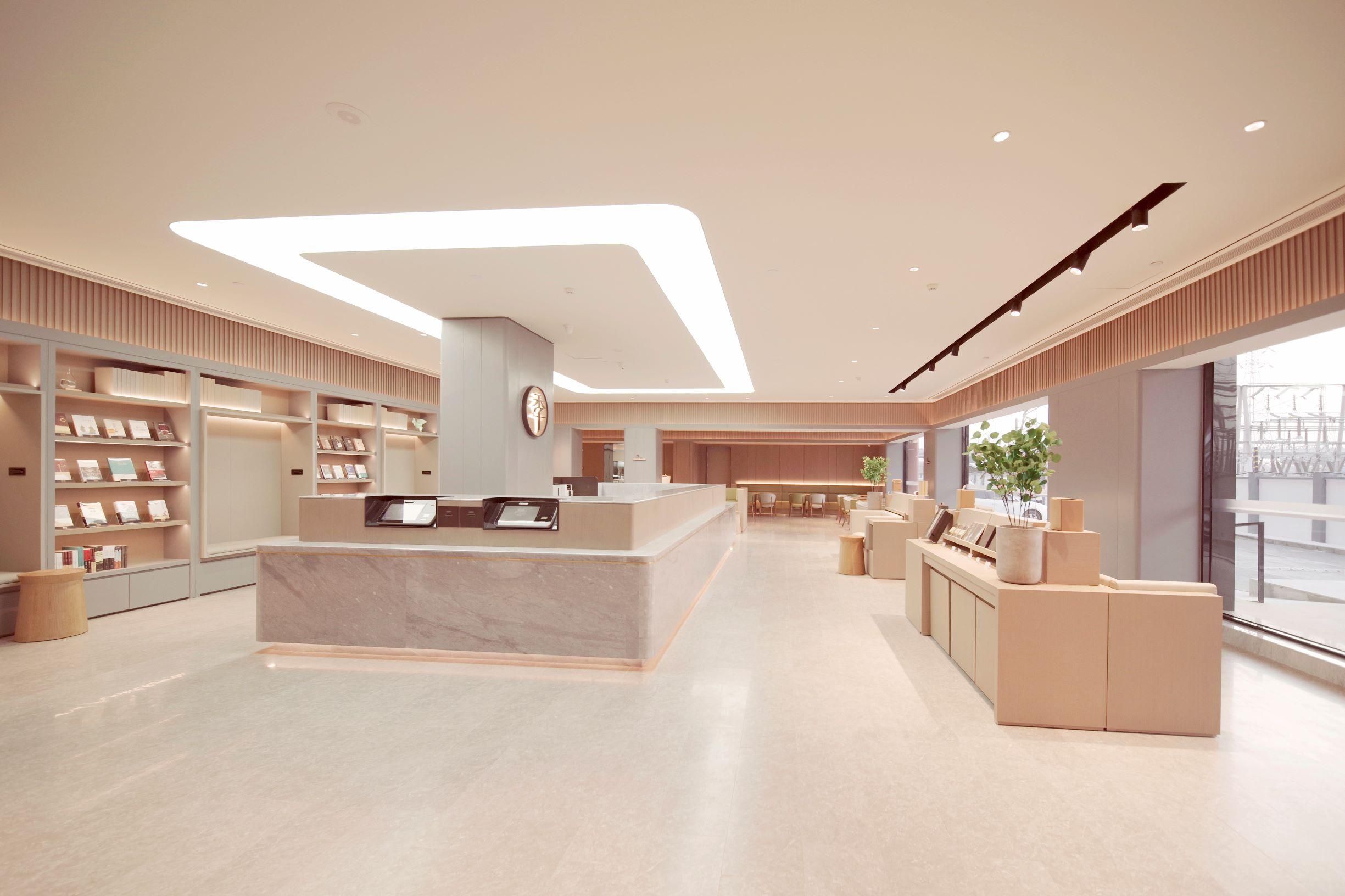 A modern hotel lobby with a reception desk, seating area, and large windows.